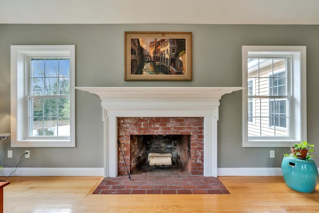 detailed view of wood finished floors, baseboards, and a fireplace with flush hearth