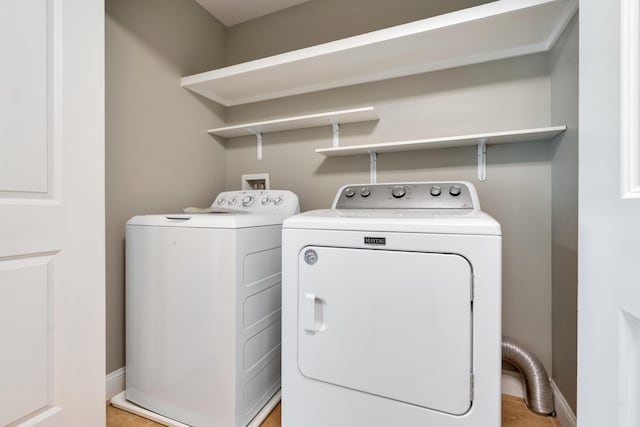 washroom with washer and clothes dryer and baseboards