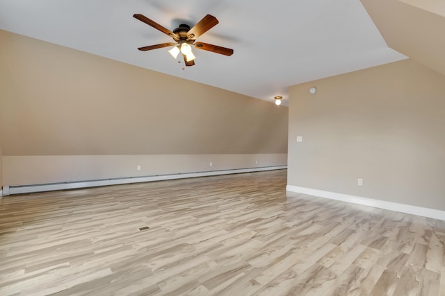 additional living space with a baseboard heating unit, vaulted ceiling, wood finished floors, ceiling fan, and baseboards
