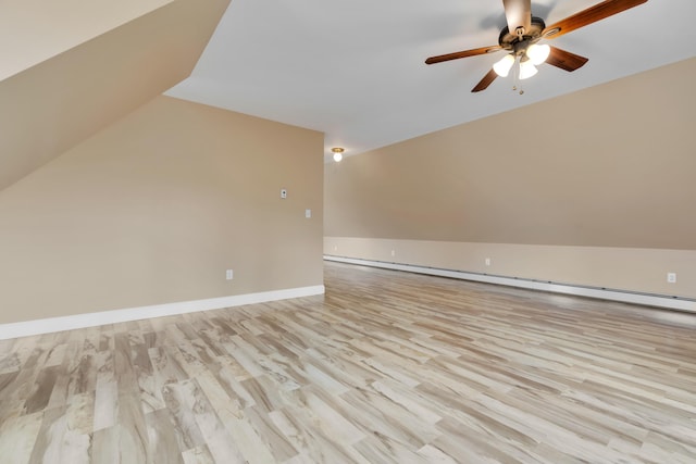 additional living space featuring wood finished floors, vaulted ceiling, ceiling fan, a baseboard radiator, and baseboards