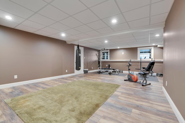 workout room featuring baseboards, wood finished floors, a paneled ceiling, and recessed lighting