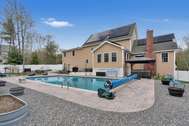 back of property featuring a covered hot tub, a patio, a gazebo, and solar panels