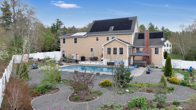 rear view of house with a hot tub, a fenced backyard, solar panels, a patio area, and a gazebo