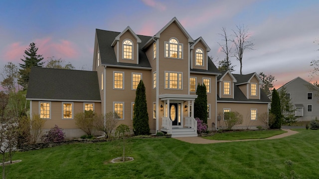 view of front of home with a yard and a shingled roof