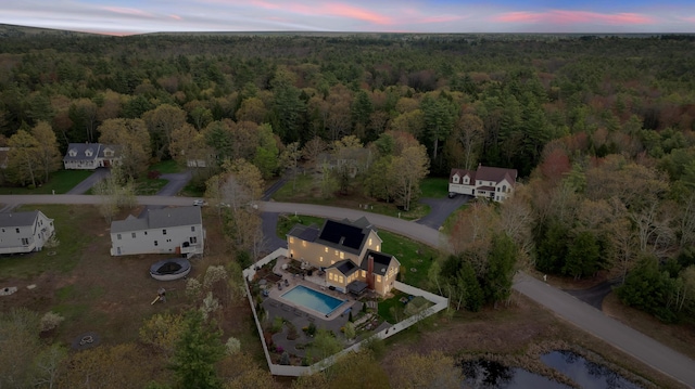view of property location with a heavily wooded area and a pool