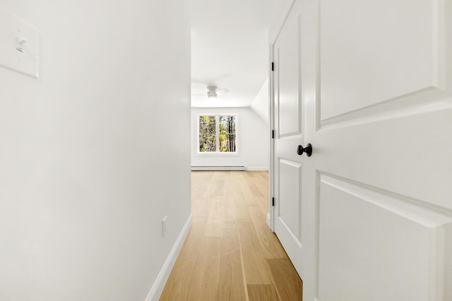 hall featuring light wood finished floors, baseboards, and a baseboard radiator