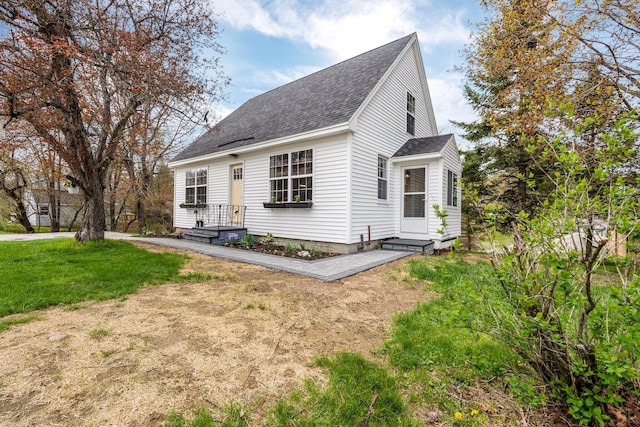 new england style home featuring a shingled roof and a front lawn