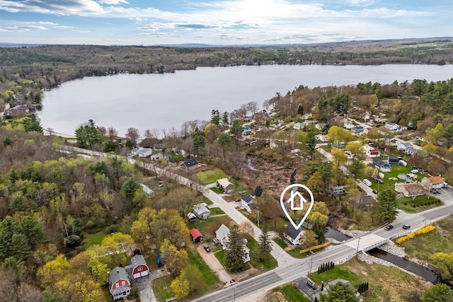 aerial view of property and surrounding area with a nearby body of water, a forest, and nearby suburban area
