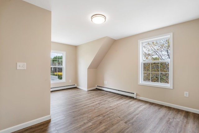 bonus room with a baseboard radiator, wood finished floors, and baseboards