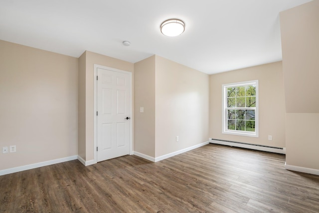 unfurnished room featuring a baseboard radiator, wood finished floors, and baseboards