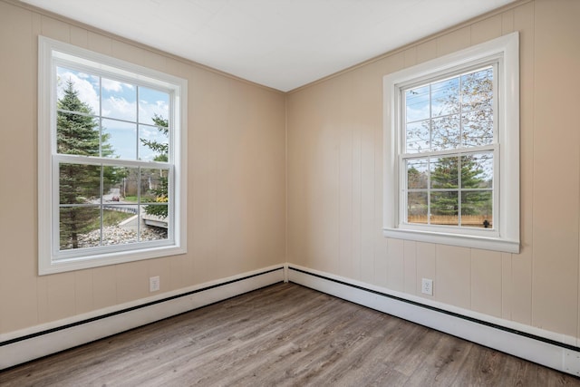 empty room featuring healthy amount of natural light, wood finished floors, and a baseboard radiator