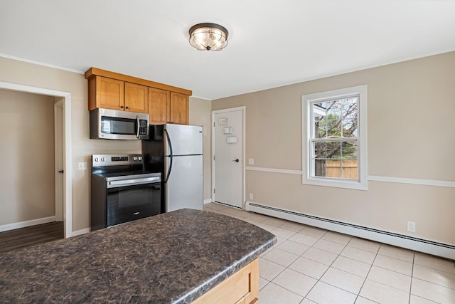 kitchen featuring appliances with stainless steel finishes, baseboard heating, brown cabinets, baseboards, and light tile patterned flooring