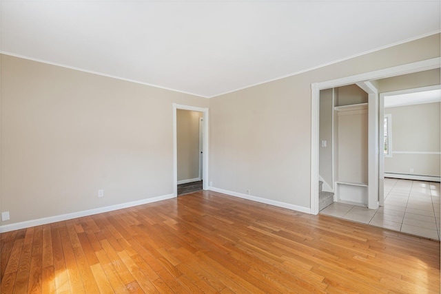 unfurnished room with light wood-style flooring, baseboards, ornamental molding, stairway, and a baseboard radiator