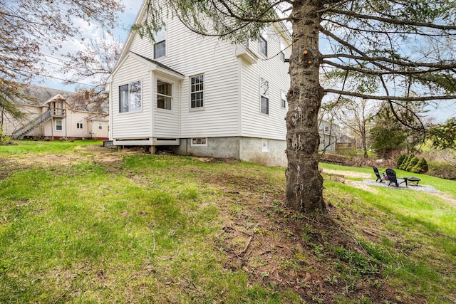 view of side of home with an outdoor fire pit and a lawn