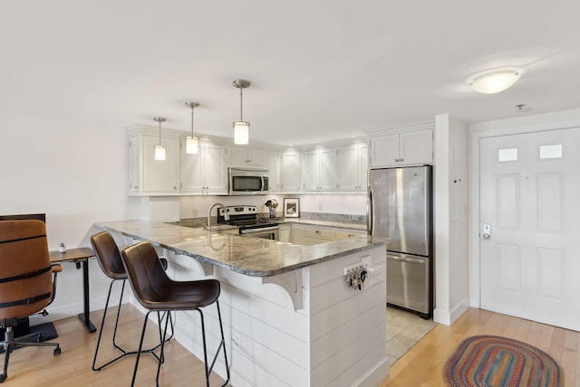 709 Chandlers Wharf Unit 709, Portland, ME 04101 - kitchen featuring stainless steel appliances, a peninsula, light wood-style flooring, and light stone countertops