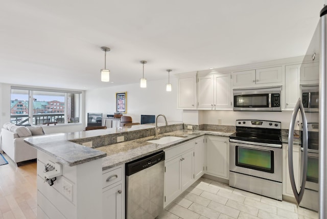 709 Chandlers Wharf Unit 709, Portland, ME 04101 - kitchen featuring appliances with stainless steel finishes, a sink, a peninsula, open floor plan, and light stone countertops