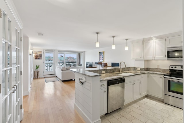 709 Chandlers Wharf Unit 709, Portland, ME 04101 - kitchen featuring stainless steel appliances, a sink, open floor plan, a peninsula, and white cabinets