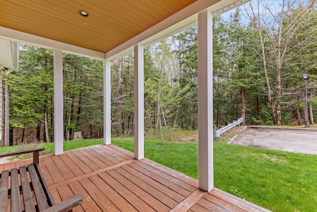 wooden deck with a forest view and a lawn