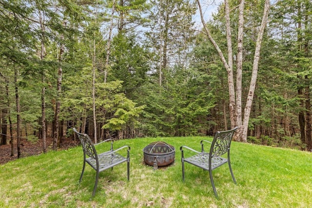 view of yard with an outdoor fire pit and a view of trees