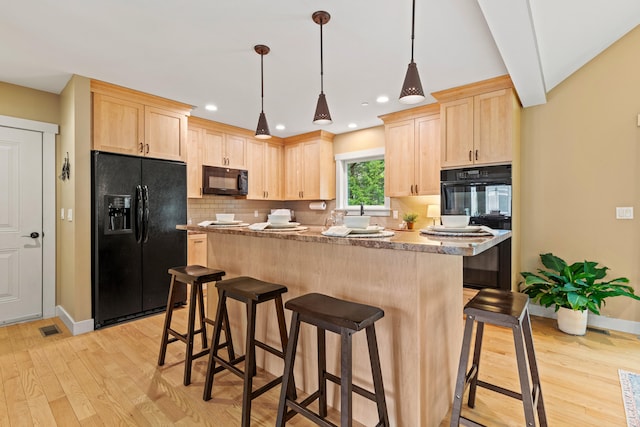 kitchen with a kitchen breakfast bar, light wood-type flooring, black appliances, light brown cabinetry, and baseboards
