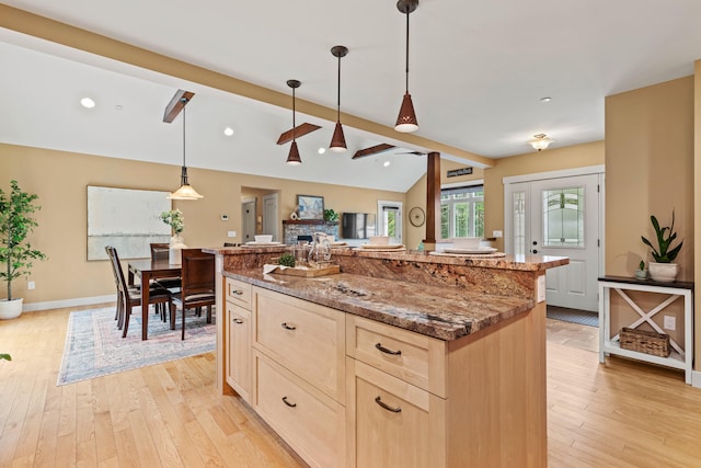 kitchen with light brown cabinetry, stone countertops, lofted ceiling with beams, light wood-type flooring, and a kitchen island