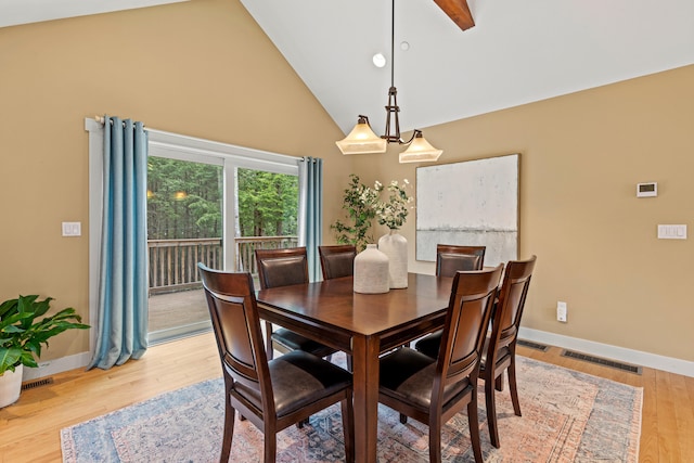 dining space with light wood-style floors, visible vents, baseboards, and high vaulted ceiling