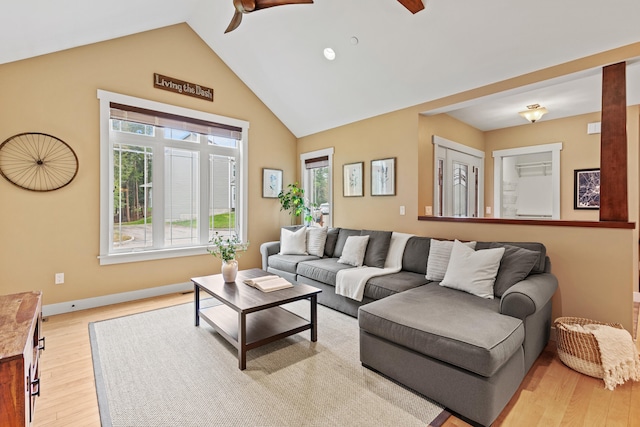 living area featuring a ceiling fan, light wood-style floors, a healthy amount of sunlight, and high vaulted ceiling