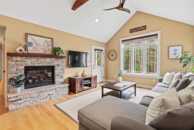 living area with wood finished floors, high vaulted ceiling, a fireplace, a ceiling fan, and baseboards