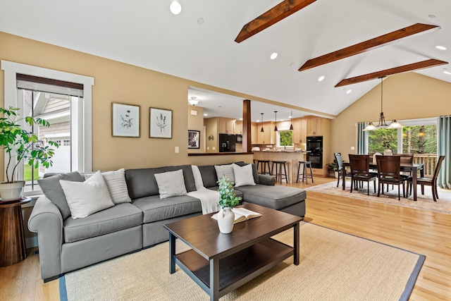 living area featuring light wood finished floors, beam ceiling, plenty of natural light, and high vaulted ceiling