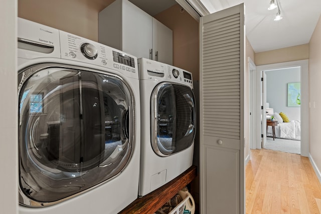 laundry area with washer and dryer, light wood-type flooring, and track lighting