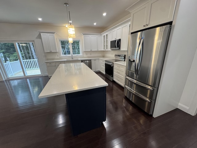 kitchen with appliances with stainless steel finishes, a center island, dark wood-type flooring, plenty of natural light, and recessed lighting