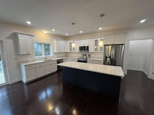 kitchen featuring stainless steel appliances, a sink, light countertops, glass insert cabinets, and a center island
