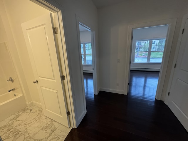 corridor featuring a baseboard radiator, plenty of natural light, and baseboards