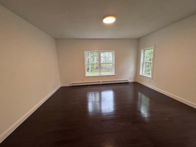 empty room with baseboard heating, dark wood-type flooring, and baseboards