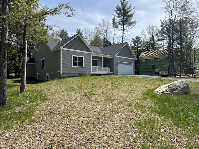 view of front of home featuring an attached garage, a front lawn, a porch, and roof with shingles