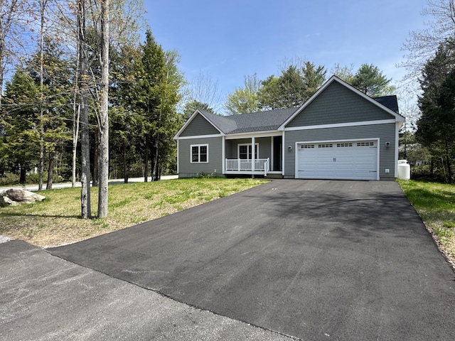 single story home with driveway, covered porch, a garage, and a front yard