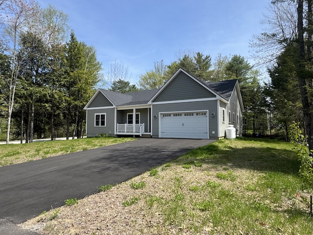 ranch-style house featuring asphalt driveway, a garage, a front yard, a porch, and roof with shingles