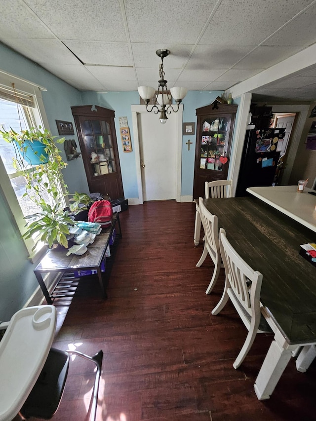 dining space with a chandelier, wood finished floors, and a paneled ceiling