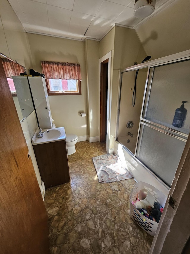 bathroom with vanity, toilet, shower / bath combination with glass door, and stone finish flooring
