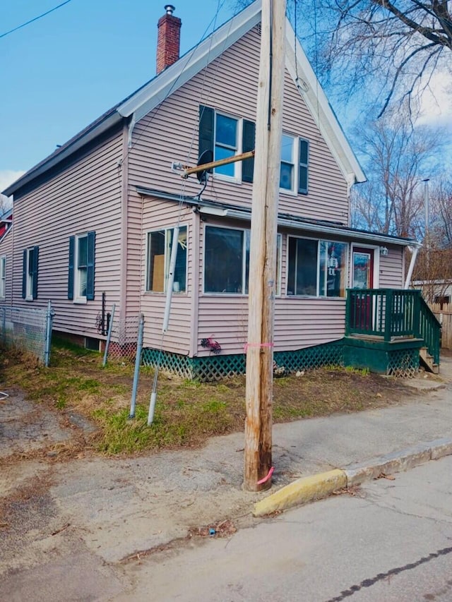 view of side of home with fence and a chimney