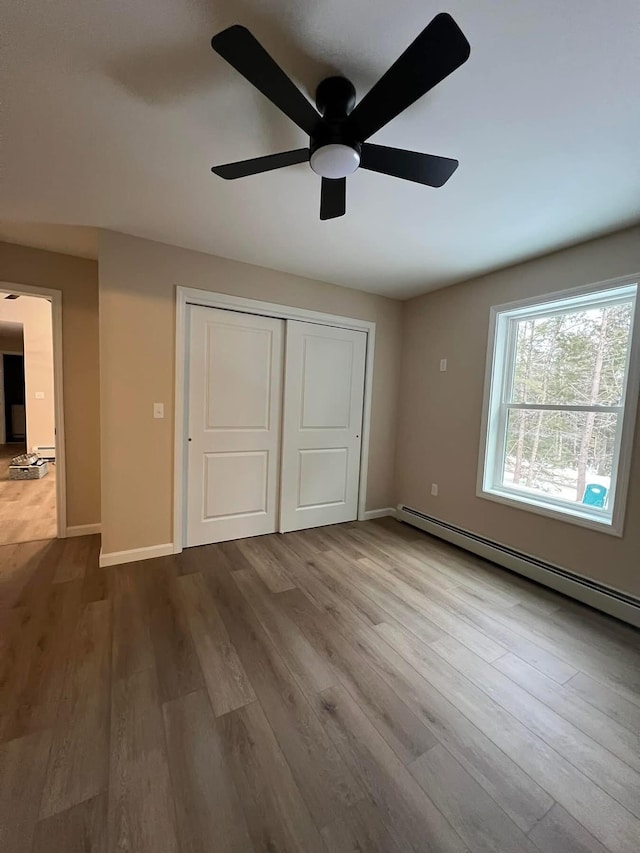 LOT22F Dunton Rd, Naples, ME 04055 - unfurnished bedroom featuring a baseboard radiator, wood finished floors, a closet, and a ceiling fan
