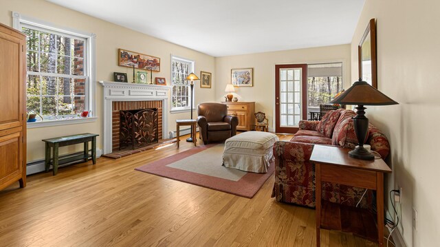 196 Eaton Ridge Dr, Holden, ME 04429 - living area with a baseboard radiator, light wood finished floors, and a fireplace