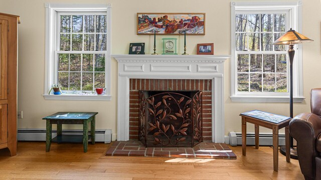 196 Eaton Ridge Dr, Holden, ME 04429 - living area with a baseboard heating unit, a brick fireplace, and light wood-style flooring