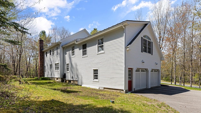 196 Eaton Ridge Dr, Holden, ME 04429 - view of property exterior featuring an attached garage, driveway, and a chimney