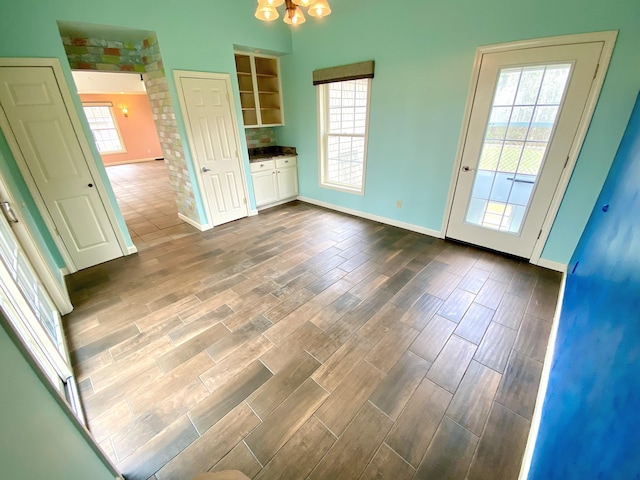 unfurnished dining area featuring baseboards, dark wood finished floors, and a chandelier