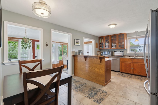 24 Ross Rd, Kennebunk, ME 04043 - kitchen with appliances with stainless steel finishes, brown cabinetry, a sink, a peninsula, and glass insert cabinets
