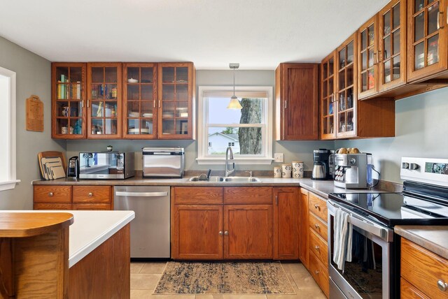 24 Ross Rd, Kennebunk, ME 04043 - kitchen featuring stainless steel appliances, a sink, brown cabinetry, and glass insert cabinets