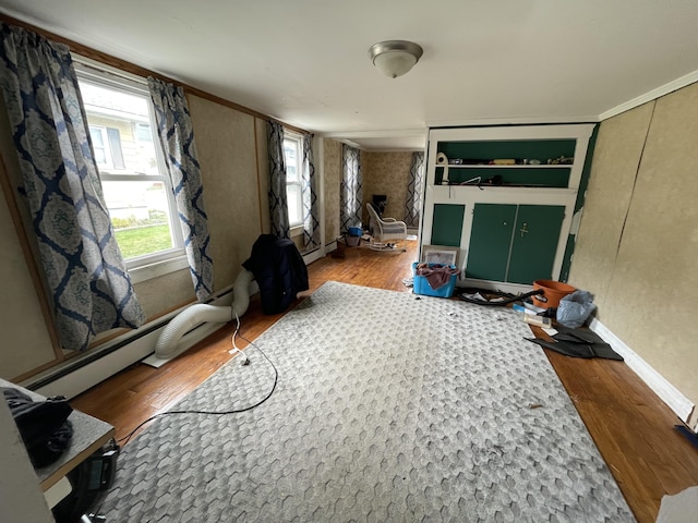 living area featuring wood finished floors, a baseboard heating unit, and baseboards