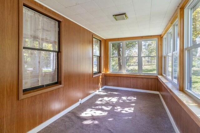 753 Sebec Village Rd, Sebec, ME 04481 - unfurnished sunroom featuring baseboards, wooden walls, and carpet floors
