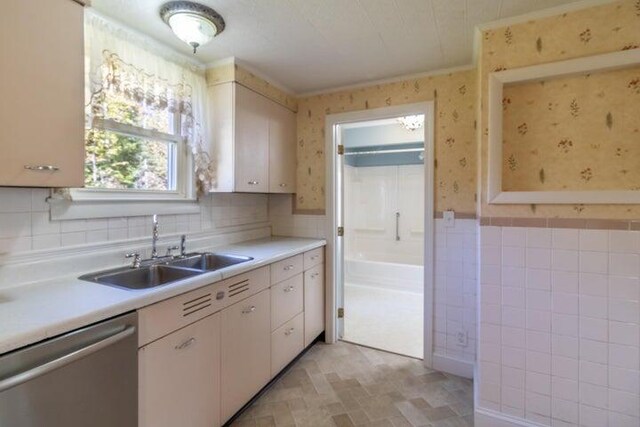 753 Sebec Village Rd, Sebec, ME 04481 - kitchen with stainless steel dishwasher, a sink, wallpapered walls, light countertops, and tile walls